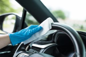 Hands with blue gloves and cleaning the car